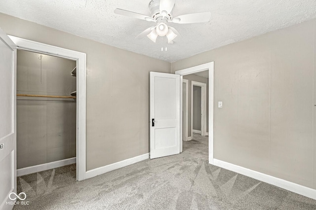 unfurnished bedroom with a closet, baseboards, ceiling fan, a textured ceiling, and carpet
