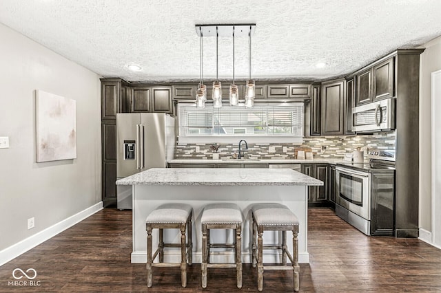 kitchen with decorative backsplash, a kitchen breakfast bar, a center island, a sink, and appliances with stainless steel finishes