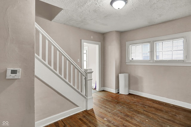 734 N Bradley Ave, Indianapolis, IN 46201 - foyer with stairway, a textured ceiling, wood-type flooring, and baseboards