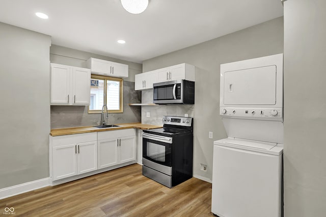 734 N Bradley Ave, Indianapolis, IN 46201 - kitchen featuring white cabinetry, stainless steel appliances, stacked washer and clothes dryer, and a sink