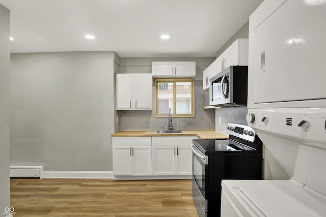 734 N Bradley Ave, Indianapolis, IN 46201 - kitchen with baseboard heating, wooden counters, a sink, stacked washer and dryer, and appliances with stainless steel finishes