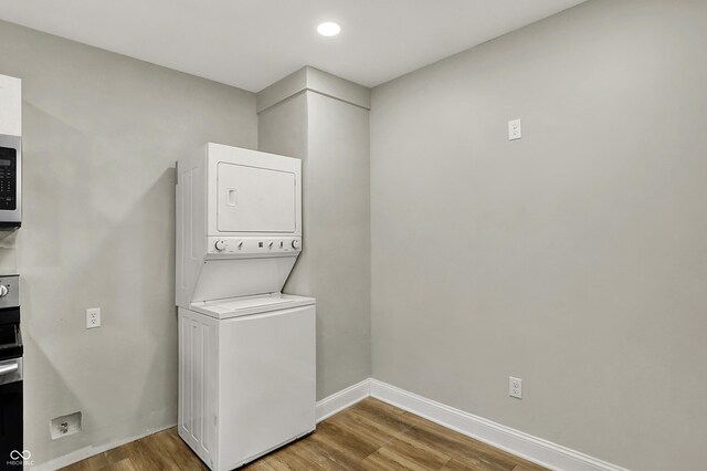 734 N Bradley Ave, Indianapolis, IN 46201 - clothes washing area with recessed lighting, baseboards, stacked washing maching and dryer, wood finished floors, and laundry area