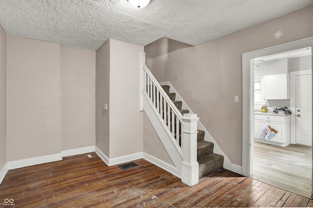 734 N Bradley Ave, Indianapolis, IN 46201 - staircase featuring a textured ceiling, visible vents, baseboards, and hardwood / wood-style flooring