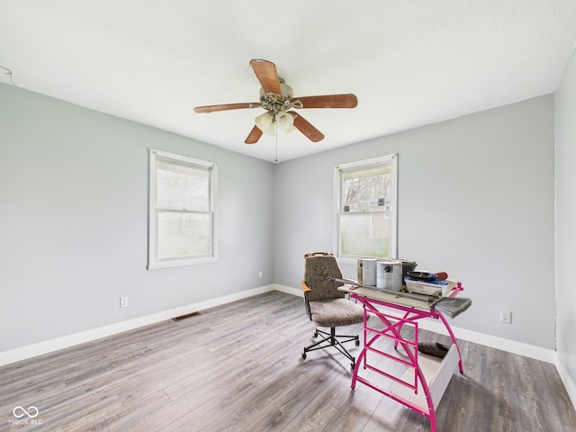 office area with wood finished floors, visible vents, a ceiling fan, and baseboards