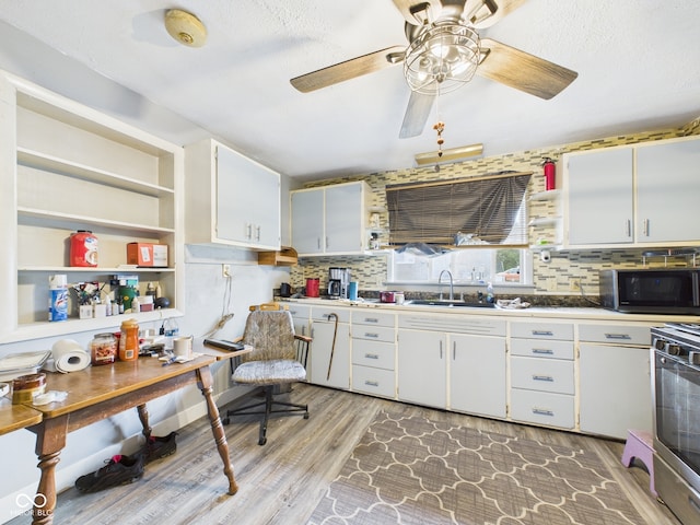 kitchen with a sink, decorative backsplash, light wood finished floors, white cabinetry, and stove