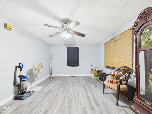unfurnished room with baseboards, a ceiling fan, wood finished floors, and a textured ceiling