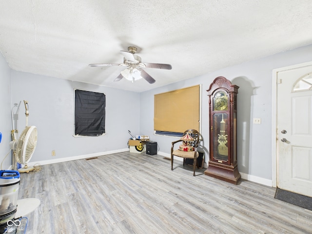 entrance foyer with baseboards, a ceiling fan, light wood-style floors, and a textured ceiling