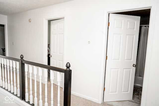 hallway with baseboards and an upstairs landing