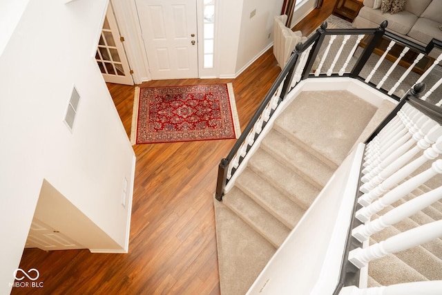 foyer entrance featuring wood finished floors, baseboards, visible vents, and stairs