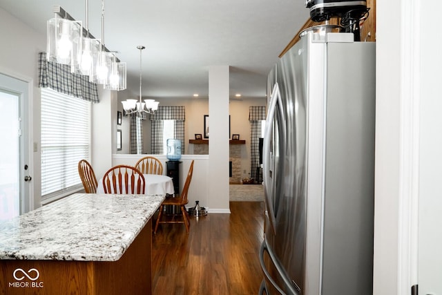 kitchen with a notable chandelier, plenty of natural light, dark wood-style flooring, and freestanding refrigerator