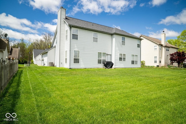 back of property with a chimney, fence, a yard, and central air condition unit