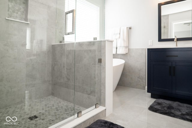 bathroom with tile walls, vanity, a freestanding tub, a stall shower, and wainscoting