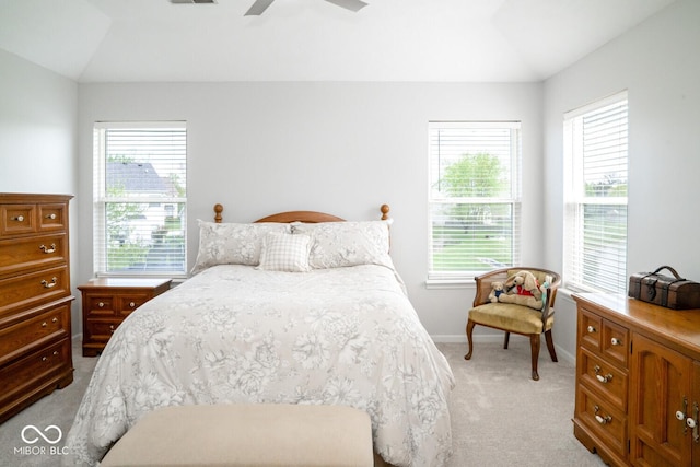 bedroom featuring multiple windows, vaulted ceiling, light carpet, and baseboards