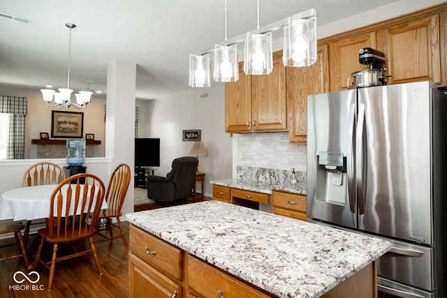 kitchen featuring light stone countertops, a chandelier, stainless steel fridge with ice dispenser, visible vents, and dark wood-type flooring