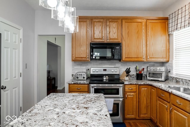 kitchen featuring tasteful backsplash, black microwave, double oven range, and light stone counters