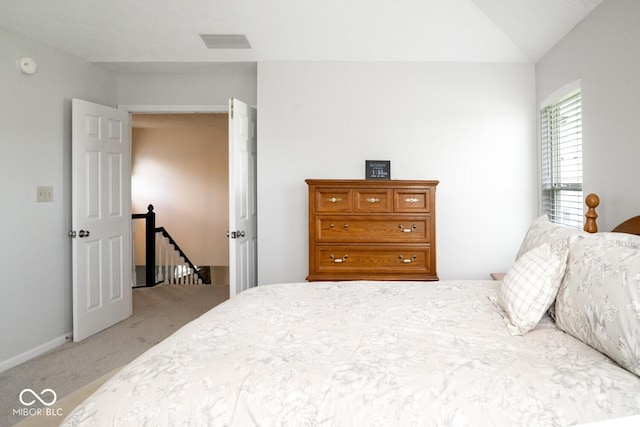 bedroom featuring visible vents, vaulted ceiling, and light carpet