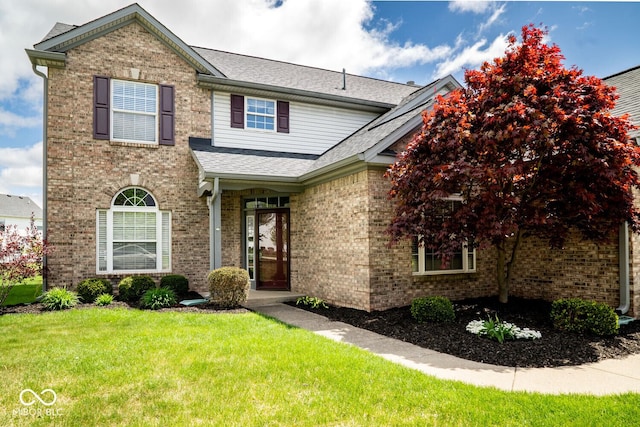 traditional-style home with brick siding, a shingled roof, and a front yard