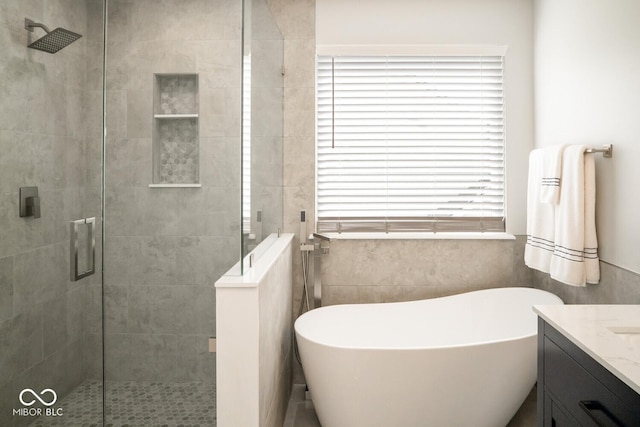 full bathroom featuring a freestanding bath, a shower stall, and vanity