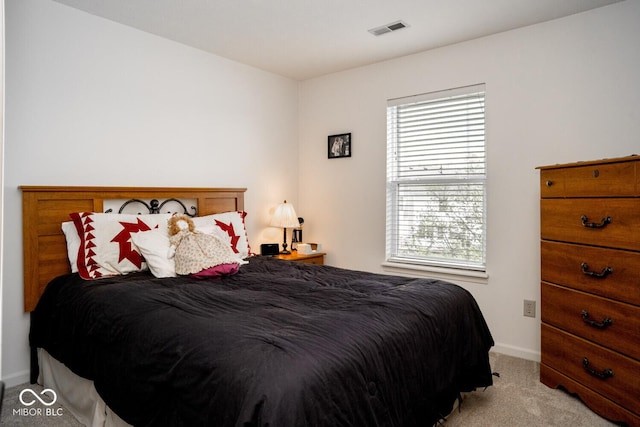 bedroom with baseboards, visible vents, and light carpet