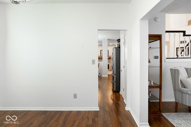 corridor with dark wood-style floors, visible vents, and baseboards