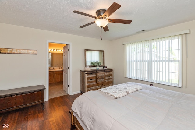 bedroom with ensuite bath, a textured ceiling, a ceiling fan, wood finished floors, and visible vents