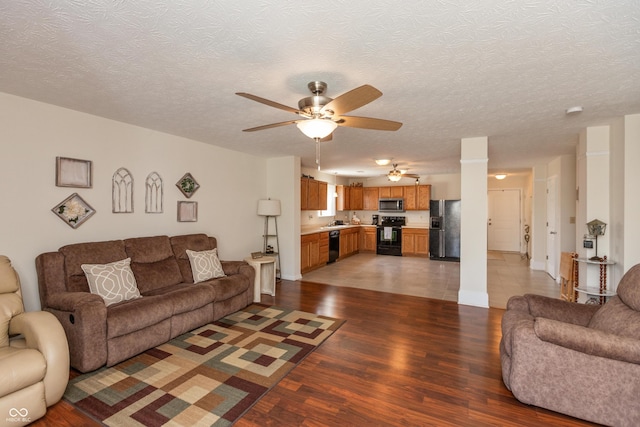 living room featuring a textured ceiling, ceiling fan, and light wood-style floors