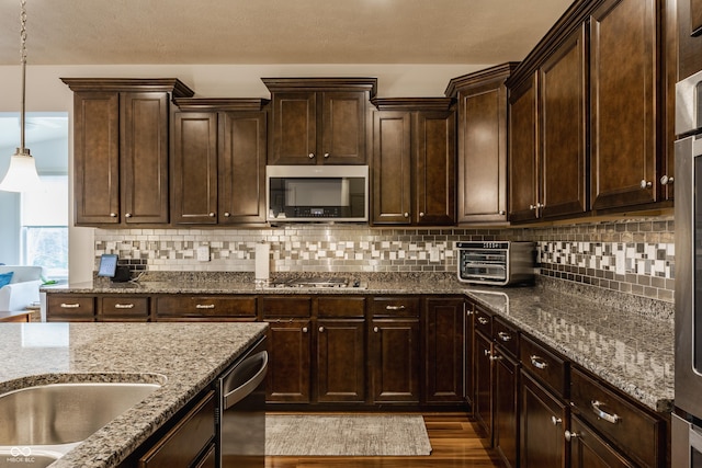 kitchen featuring a toaster, stainless steel appliances, stone countertops, and dark brown cabinets