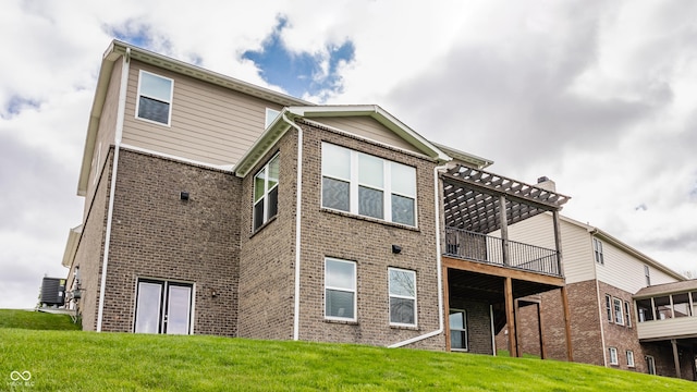 back of property featuring a deck, brick siding, and a yard