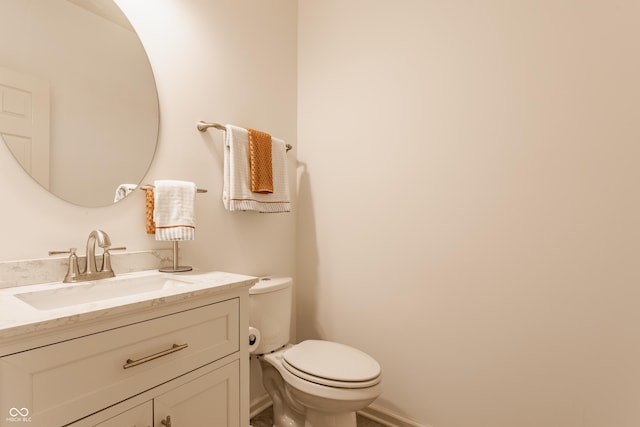 bathroom with toilet, vanity, and baseboards
