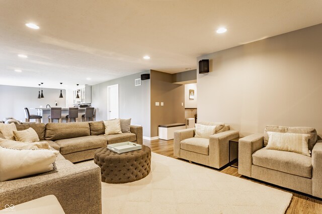 living area featuring visible vents, light wood-type flooring, recessed lighting, and baseboards