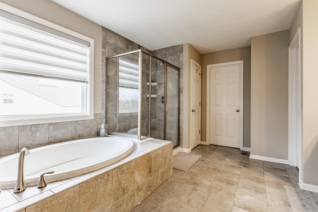 bathroom featuring a garden tub, a stall shower, and baseboards