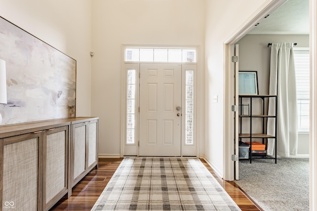 foyer entrance featuring a towering ceiling, baseboards, and dark wood finished floors