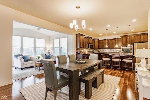 dining area with dark wood finished floors, recessed lighting, ceiling fan with notable chandelier, and lofted ceiling