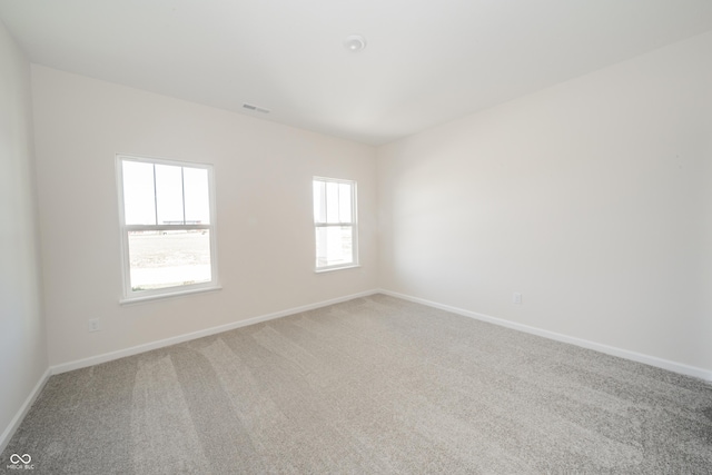 unfurnished room featuring visible vents, baseboards, and light carpet