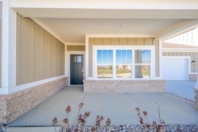property entrance featuring board and batten siding, brick siding, and a garage