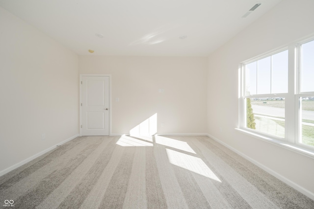 unfurnished room with light colored carpet, baseboards, and visible vents