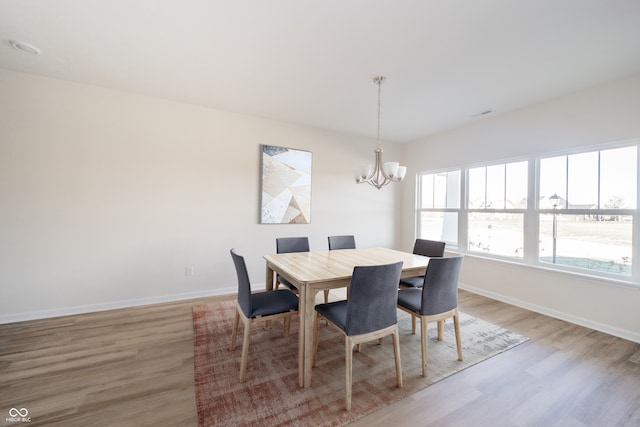 dining space with baseboards, a notable chandelier, and light wood-style flooring