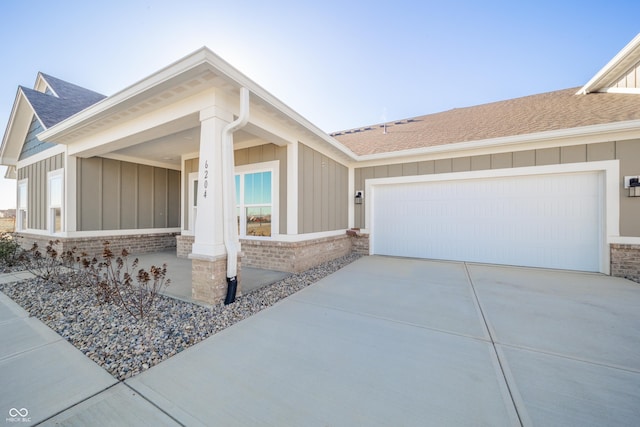 view of front of house with roof with shingles, board and batten siding, driveway, and a garage