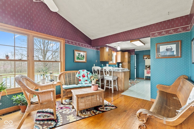 1301 N Maple St, Veedersburg, IN 47987 - living area featuring vaulted ceiling, visible vents, wood finished floors, and wallpapered walls