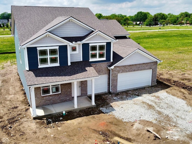 210 Aster Way, Greenfield, IN 46140 - view of front of home featuring covered porch, an attached garage, brick siding, a front lawn, and a shingled roof