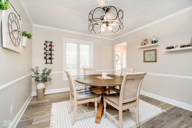 dining room with crown molding, light wood finished floors, baseboards, and an inviting chandelier