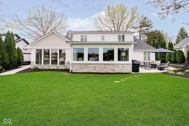 rear view of property with a yard, stone siding, and a patio area