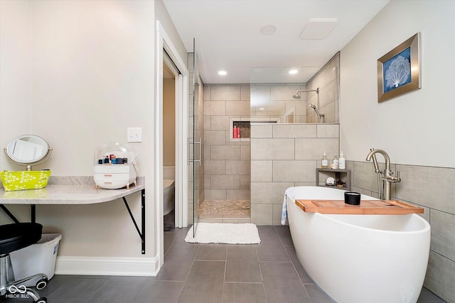 bathroom with toilet, tile walls, a freestanding tub, tile patterned flooring, and a walk in shower