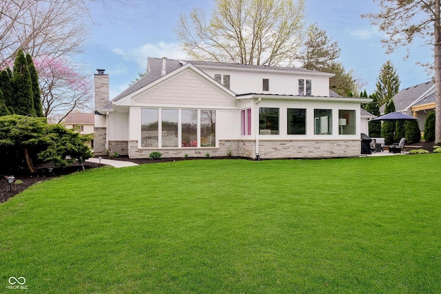 rear view of house featuring a chimney, stone siding, and a lawn