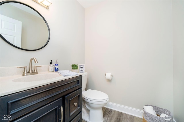 bathroom featuring baseboards, wood finished floors, vanity, and toilet