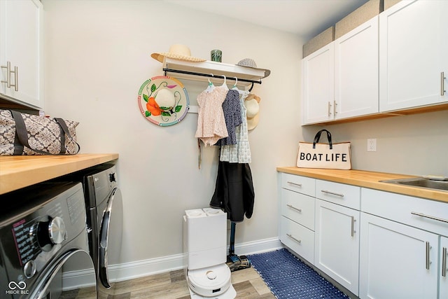 laundry area with a sink, light wood-type flooring, baseboards, washer and dryer, and cabinet space
