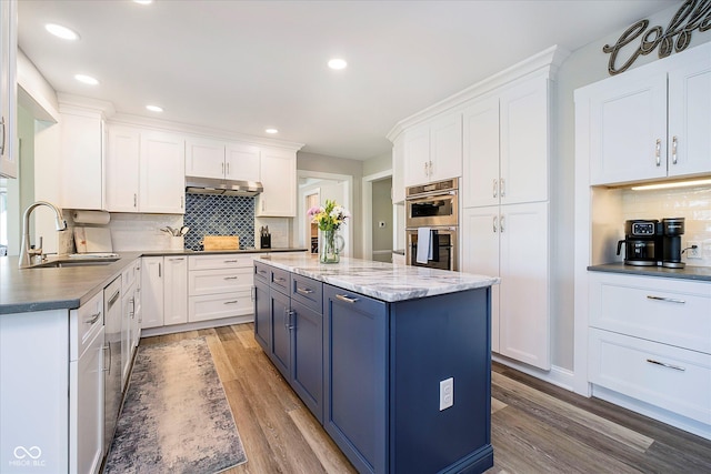 kitchen with blue cabinets, white cabinets, a sink, and light wood-style flooring