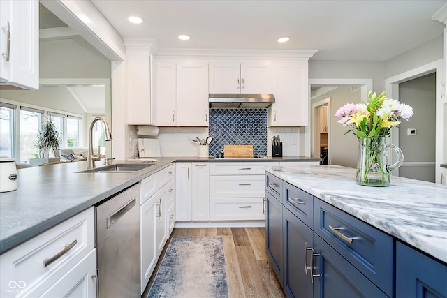 kitchen with stainless steel dishwasher, a sink, light wood-style flooring, blue cabinetry, and under cabinet range hood