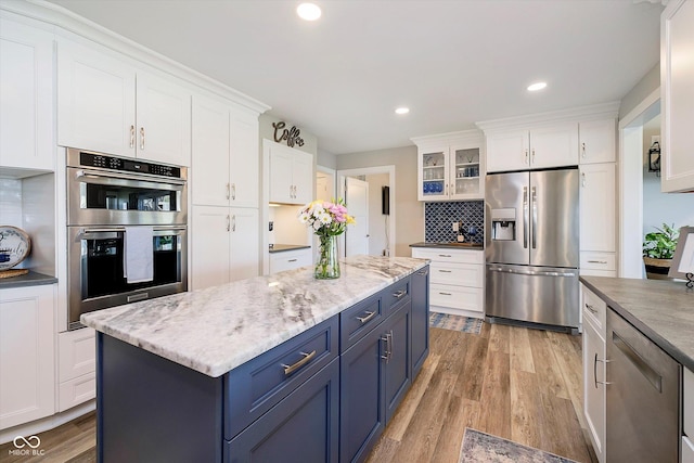 kitchen with light wood-type flooring, white cabinetry, blue cabinets, and stainless steel appliances