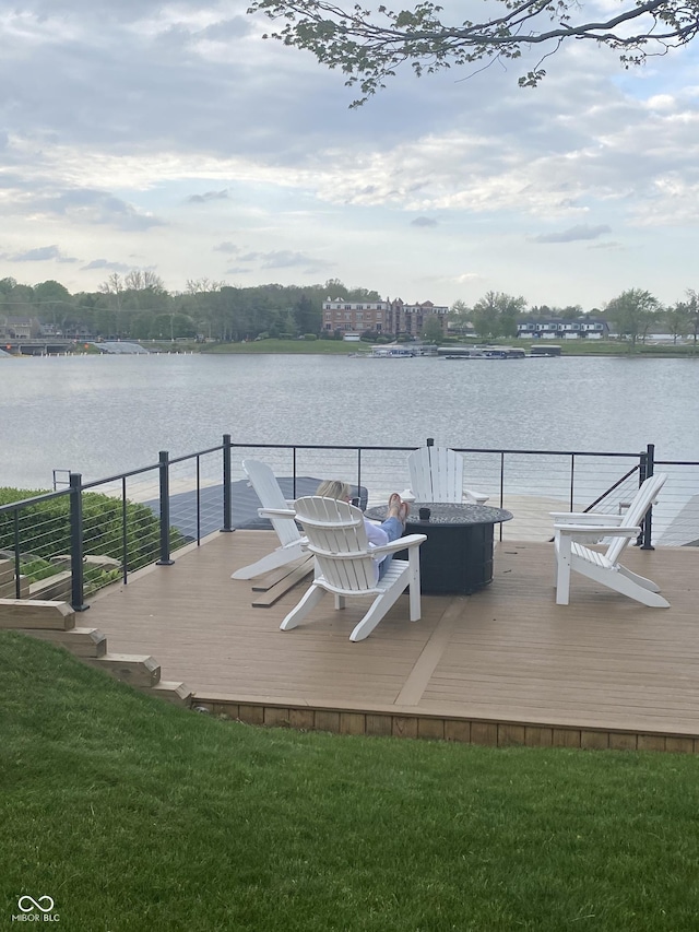dock area featuring an outdoor fire pit, a deck with water view, and a yard